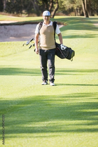 Portrait of sportsman walking with his golf bag