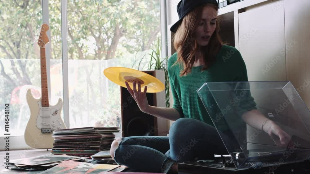 Young woman sitting nearby record player and changing record