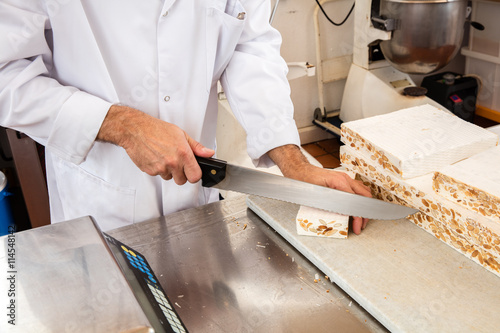 hands of professional nougat maker cutting and slicing portions