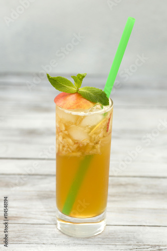 Fresh apple juice in a glass with straw on wood background