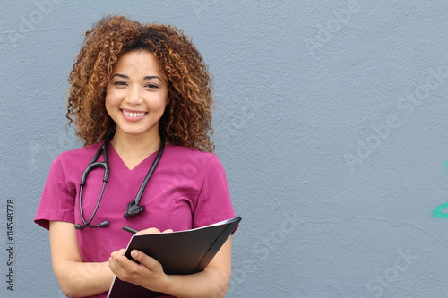 Beautiful african american female pediatric nurse holding pen and paper taking notes