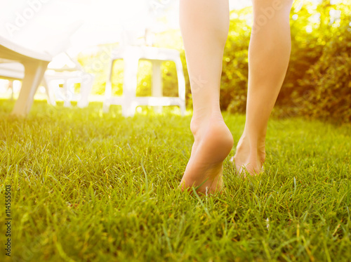 Close up female legs walking on the grass. photo