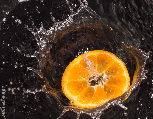 Fototapeta Naklejka Na Ścianę i Meble -  Orange in water splashes on a black background