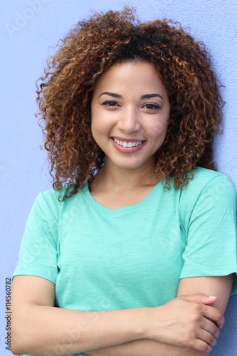 Latin girl with blond afro hair style smiling portrait on a blue background
