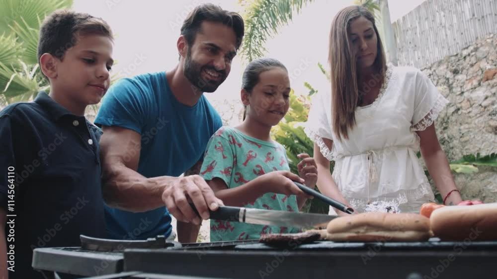 Family cooking hamburger on barbecue grill