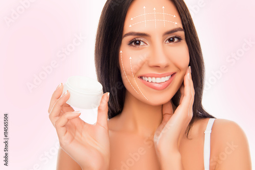 Close-up photo of sensetive pretty woman holding jar of cream an