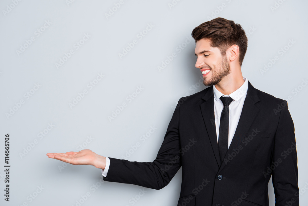 Cheerful young man in black suit presenting product Cheerful young man in black suit presenting product
