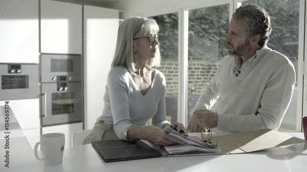 Adult male with senior female looking at personal finance in kitchen Adult male with senior female looking at personal finance in kitchen