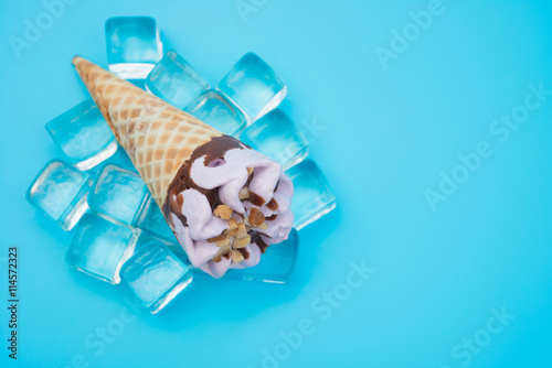 top view peanut flavor ice cream cone on top of ice cubes on blue background with copy space