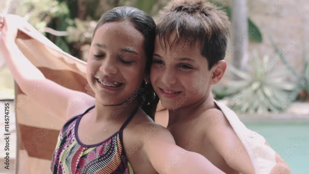 Sibling wrapped in towel and enjoying near swimming pool Sibling wrapped in towel and enjoying near swimming pool