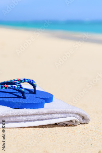 A pair of blue flip flops on a white towel at the beach