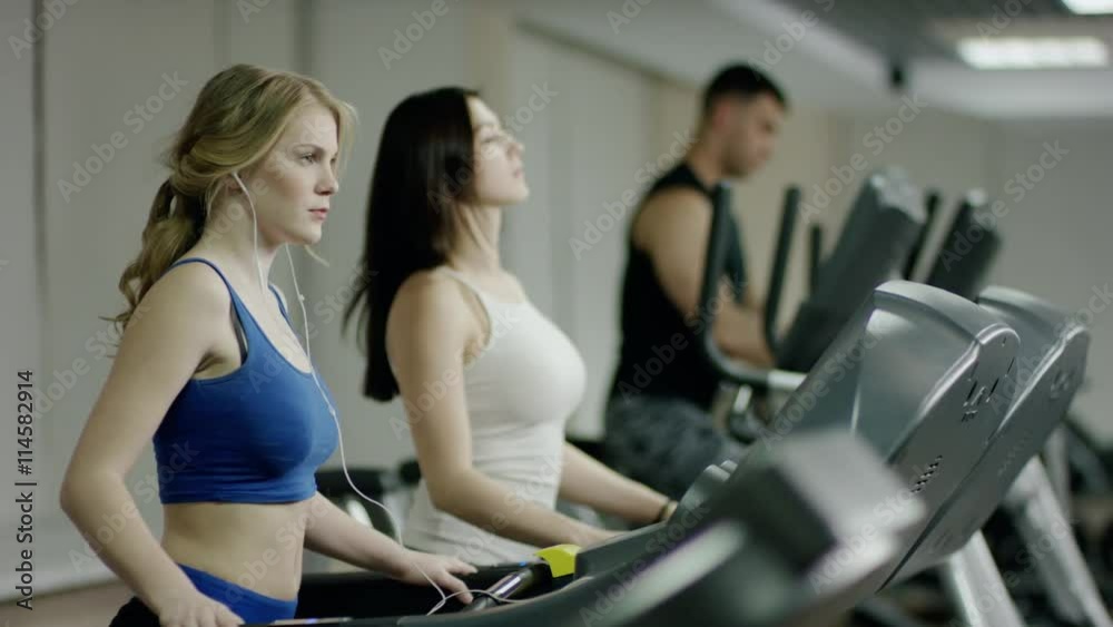 woman in headphones walking on a treadmill woman in headphones walking on a treadmill
