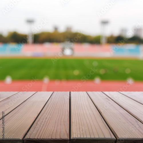 Wood table top on blur background of football field in stadium.