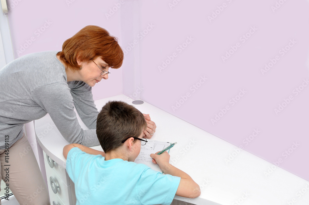 Woman helping young schoolboy to do his homework. Background with copy space on the right side. Woman helping young schoolboy to do his homework. Background with copy space on the right side.