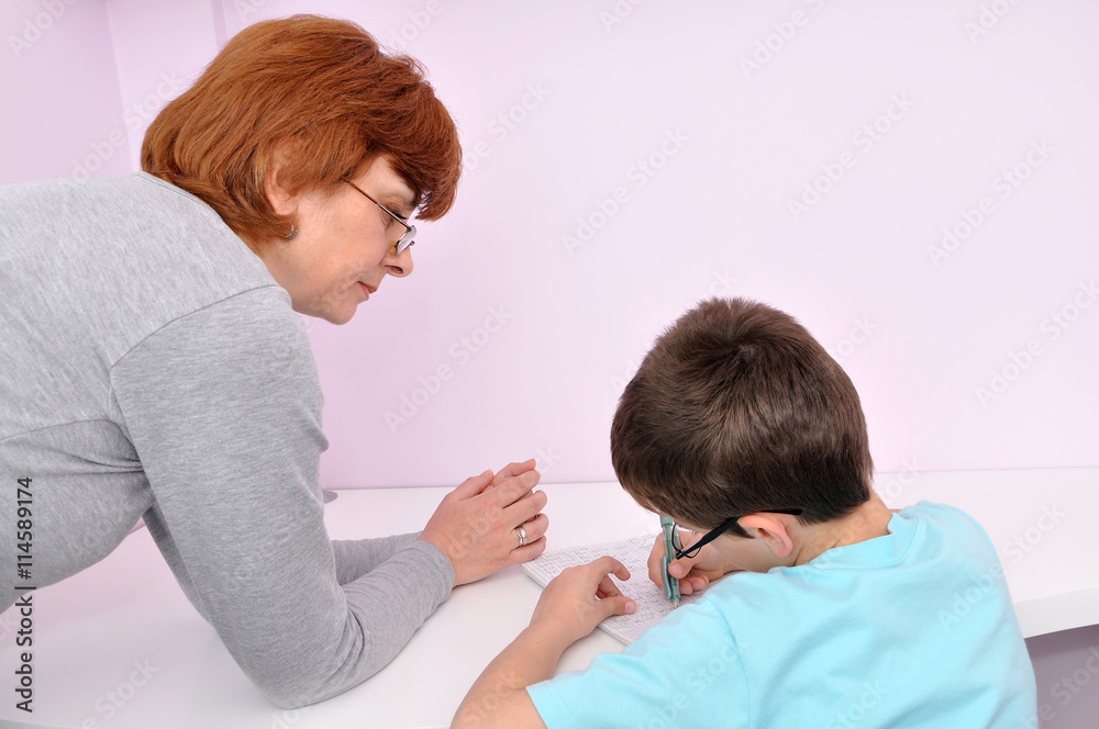 Woman helping young schoolboy to do his homework. Background with copy space on the right side. Woman helping young schoolboy to do his homework. Background with copy space on the right side.