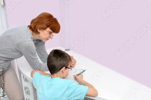 Woman helping young schoolboy to do his homework. Background with copy space on the right side.