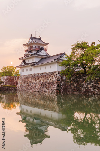 Toyama castle with beautiful sunset and reflection in water.