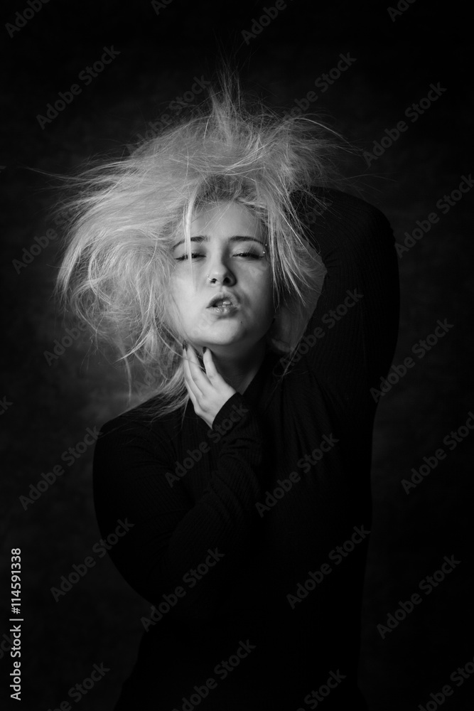 Sexy young woman putting hands in her disheveled hair. Sexy look in black and white portrait.