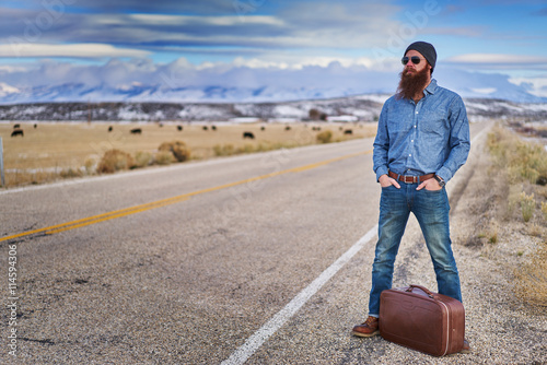 bearded traveling guy waiting along side empty american road in nevada