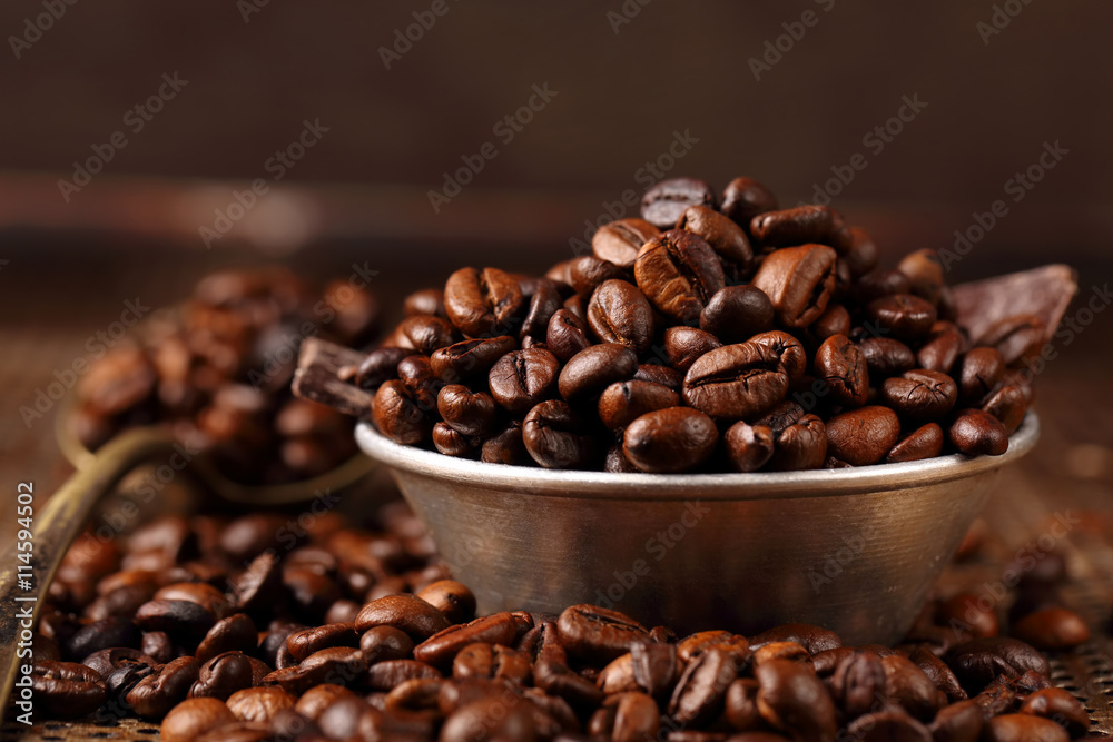 Fototapeta premium Coffee beans in a bowl on brown vintage background