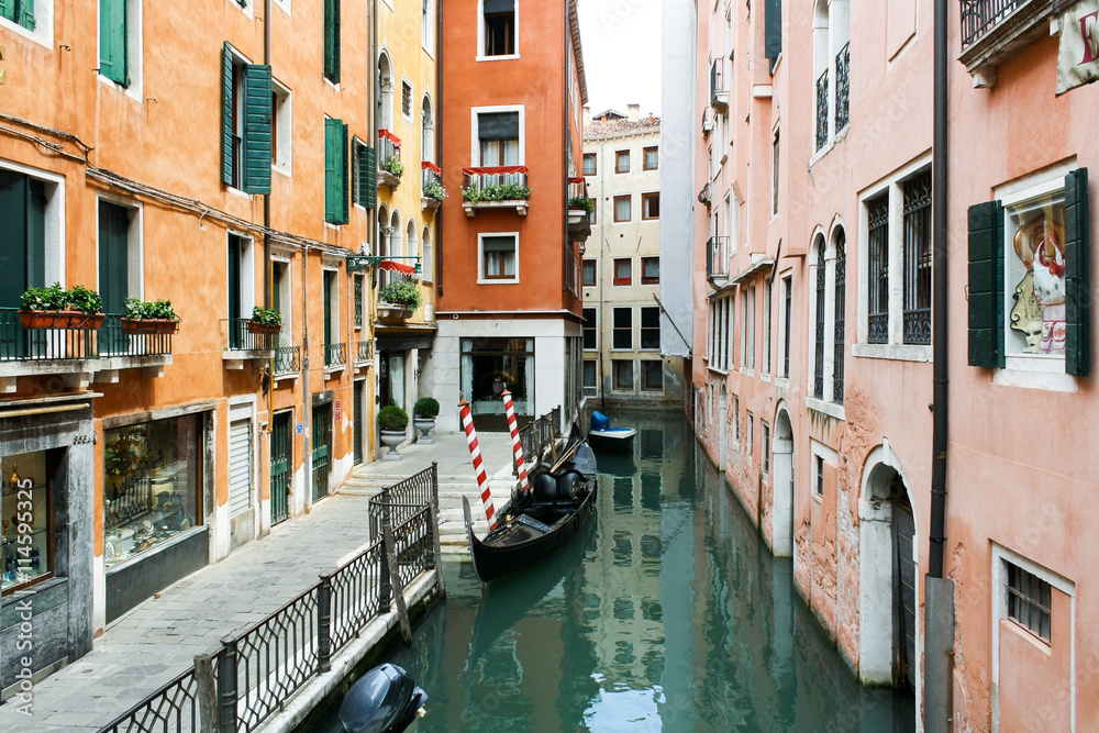 Narrow Venetian canal, colorful houses and gondola