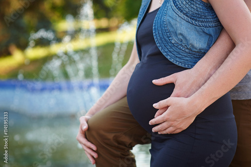 Pregnant woman and husband holding hands on belly