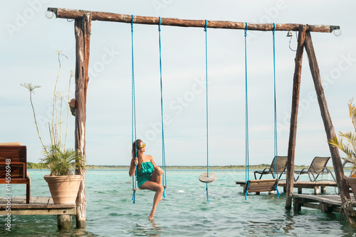 Beautiful woman on the swings which above a water