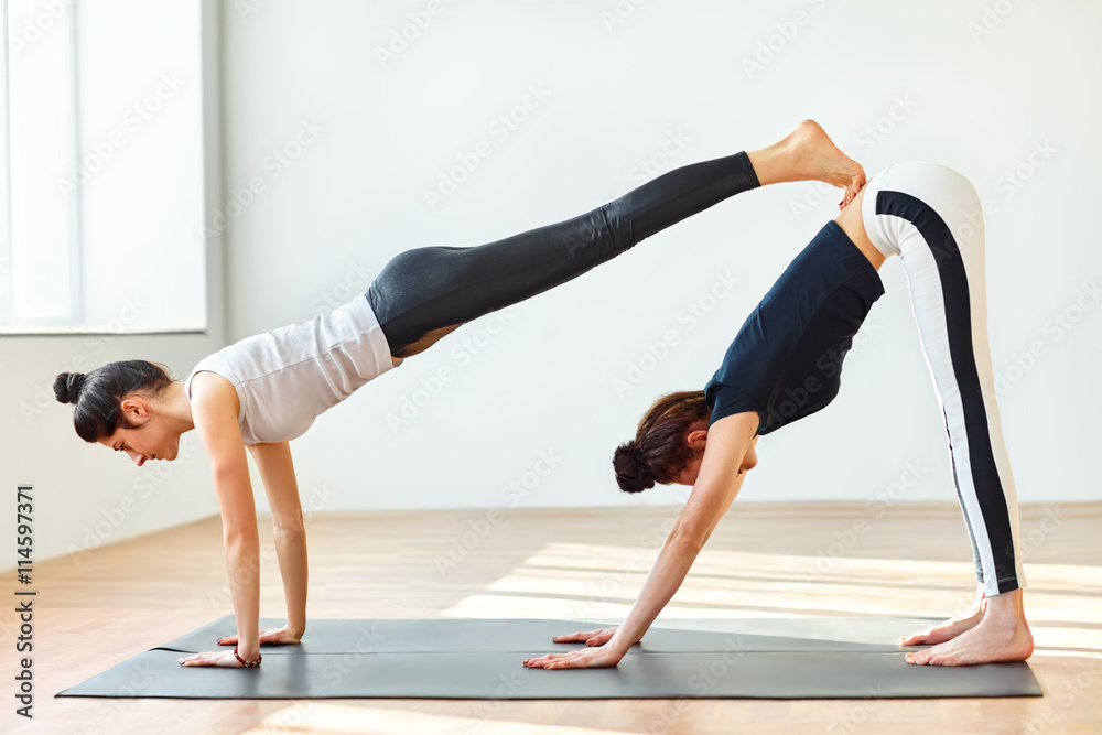 Two young women doing yoga asana double downward dog Two young women doing yoga asana double downward dog