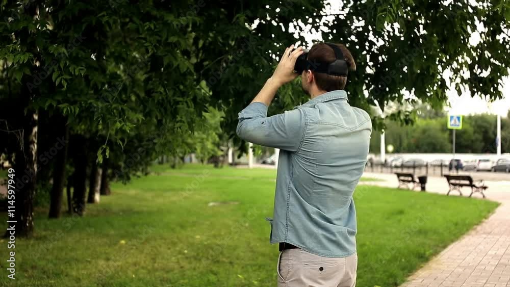 Young handsome man wearing virtual reality headset in a city park with copyspace Young handsome man wearing virtual reality headset in a city park with copyspace