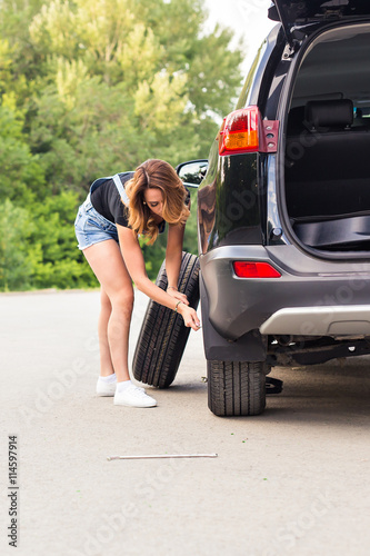 Woman changing tire on a road © satura_