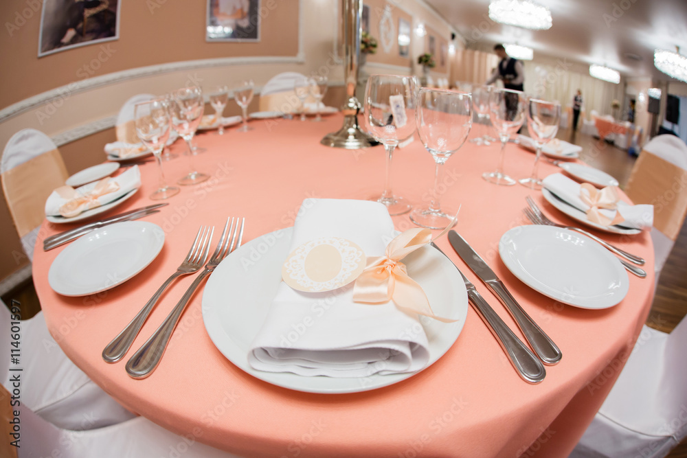 Fototapeta premium Plate with napkin with pink ribbon on wedding table in restaurant