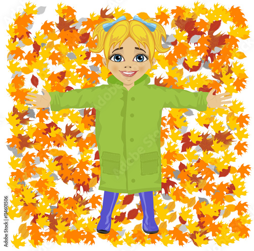 Cute little girl wearing green raincoat lying on colorful autumn leaves in park