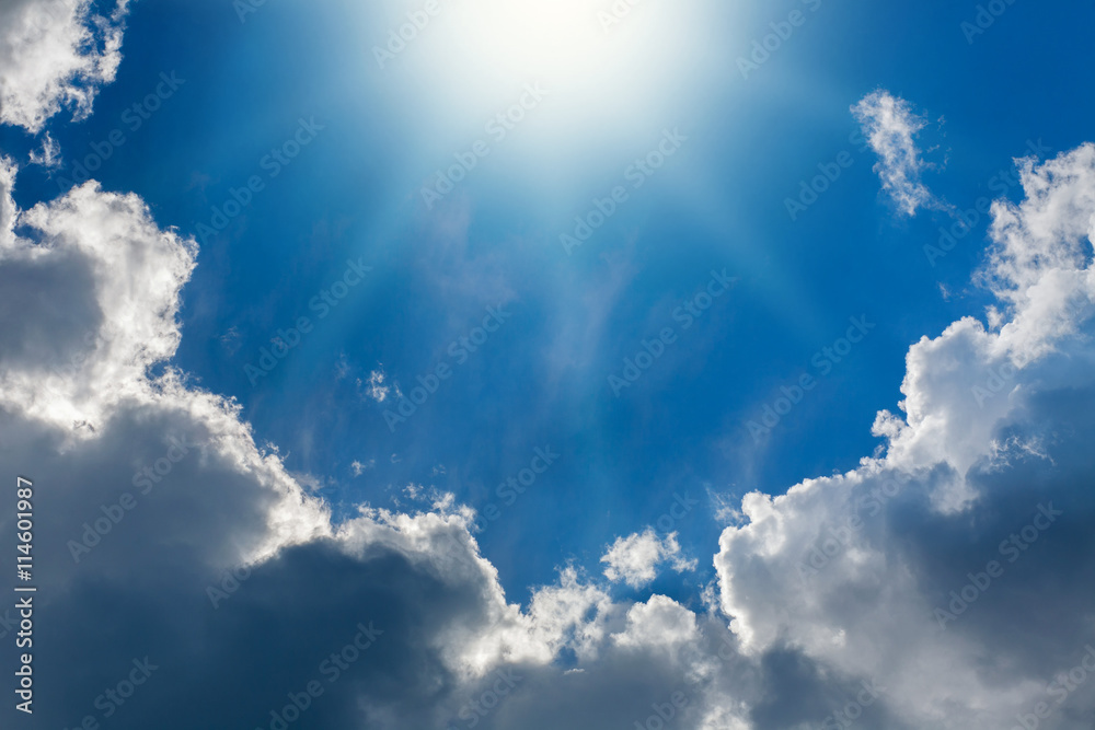 Fototapeta premium Shining sun on background of blue sky and white clouds