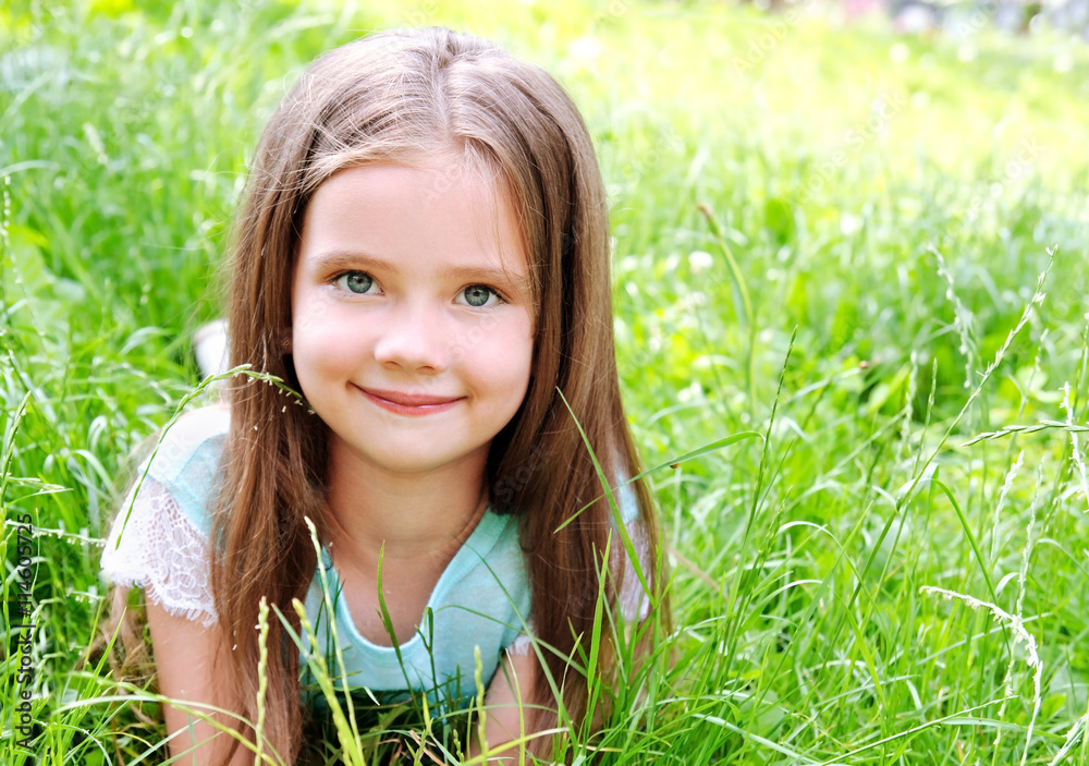Adorable smiling little girl lying on grass in summer day Adorable smiling little girl lying on grass in summer day