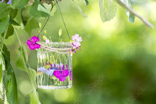 Blumen im Glas an einem Baum im Garten