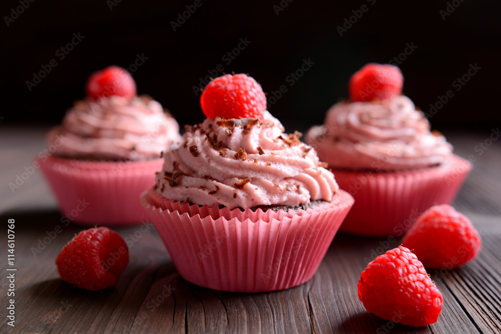 Raspberry cupcakes sprinkled with chocolate on dark background