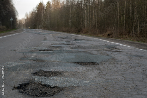 Potholes on the road. Broken russian road.
