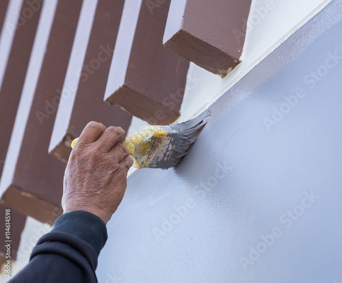 Hand holding brush painting wall