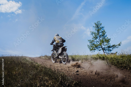 rider going uphill from under rear wheels of mud and stones