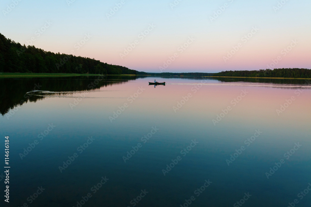 Lonely boat on calm lake at sunset