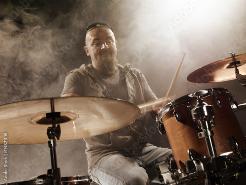 Silhouette of the drummer on stage. Dark background, smoke, spotlights