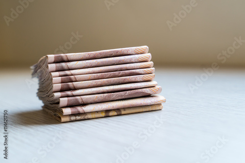 Stack of thousand bath Thai money on wooden table with copy space