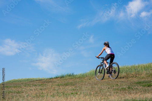 Sport bike woman on the meadow with a beautiful landscape
