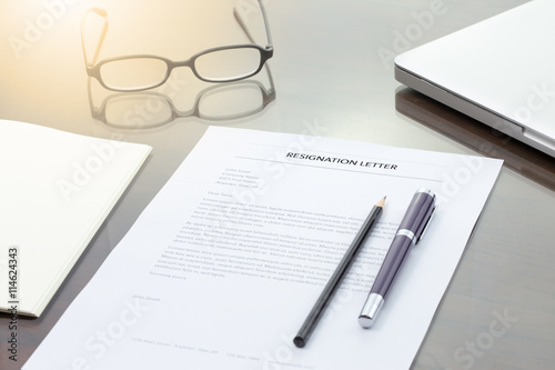 Resignation letter information with pen, pencil, computer laptop and glasses.