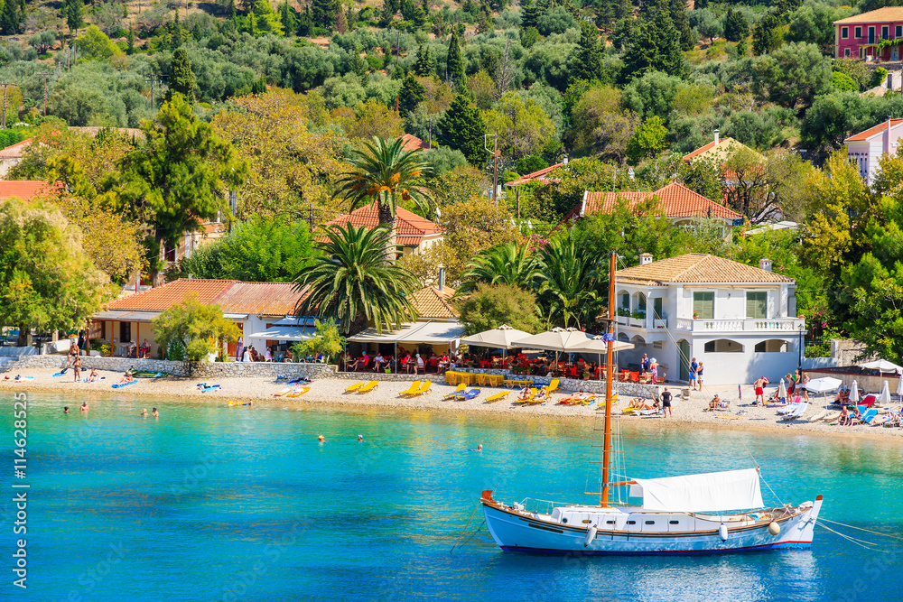 Traditional white yacht boat on turquoise sea in Assos village, Kefalonia island, Greece
