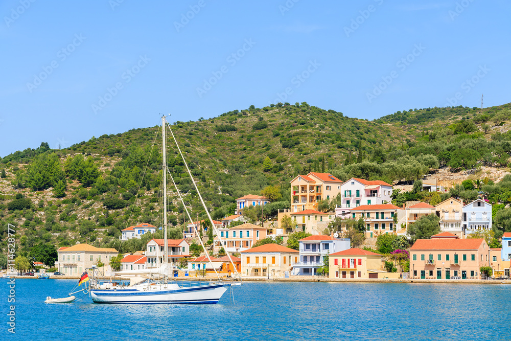Yacht boat on sea with colorful houses of Vathi town in background, Ithaka island, Greece