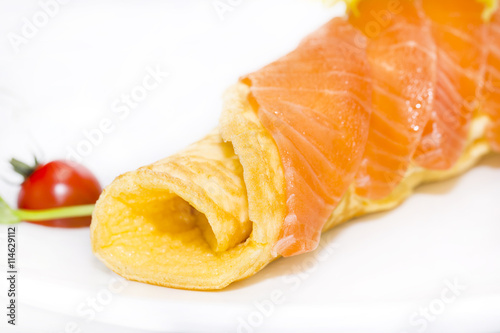 scrambled eggs with cheese and salmon decorated with tomato on white background