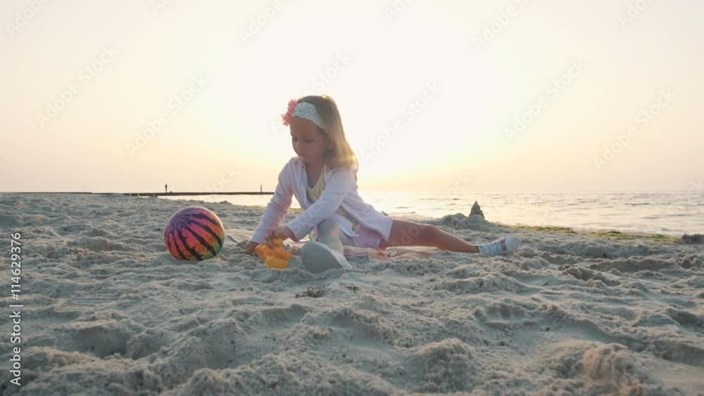 Little girl playin on the beach near the water on the sand