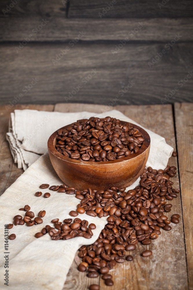 Roasted coffee beans in a wooden bowl on wooden background Roasted coffee beans in a wooden bowl on wooden background