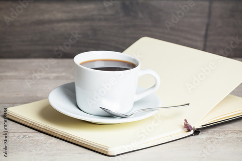 Cup of coffee on a wooden table with book